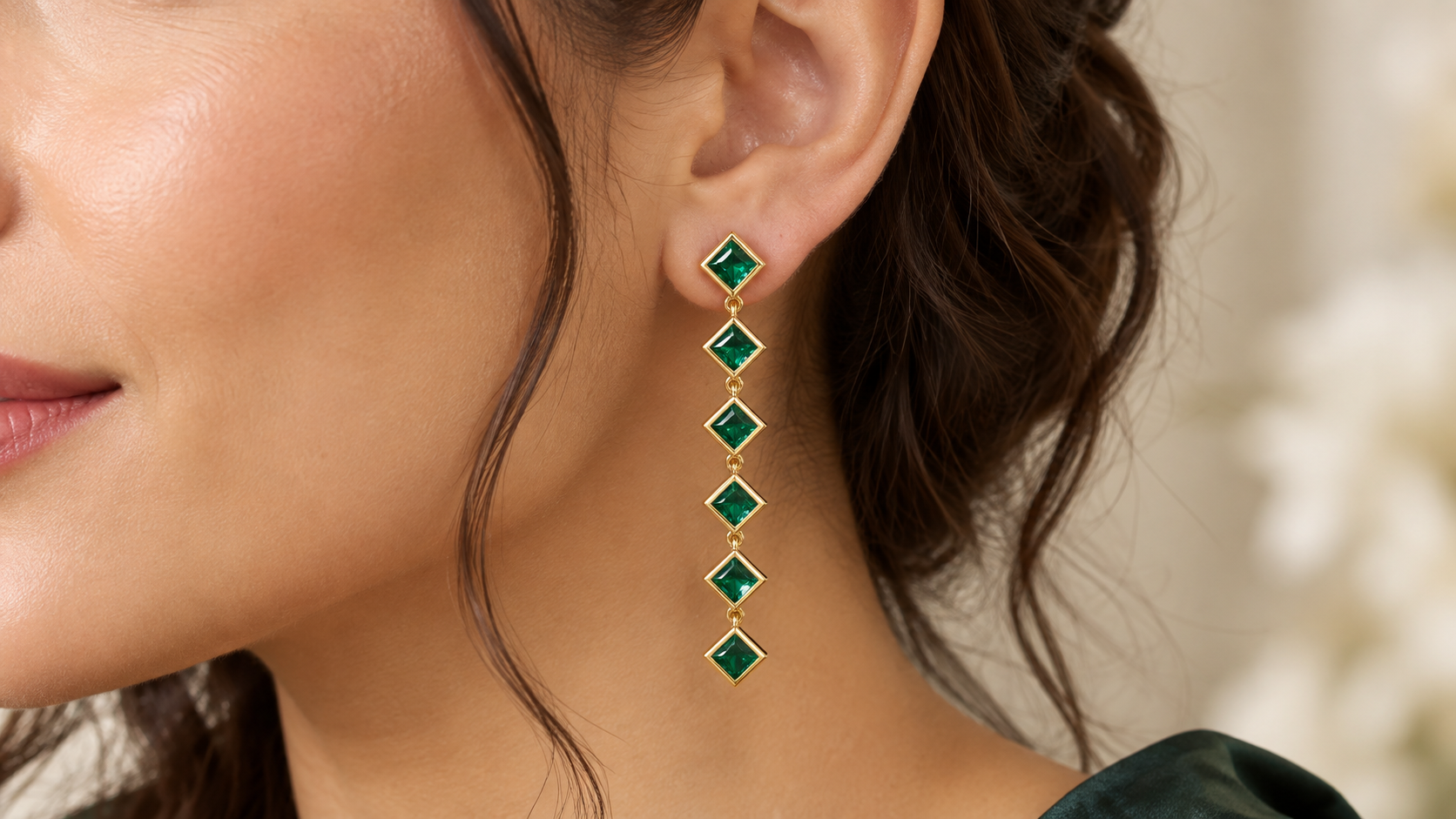 Green gemstone earrings in Central Valley featuring a long, geometric design with gold-toned detailing.